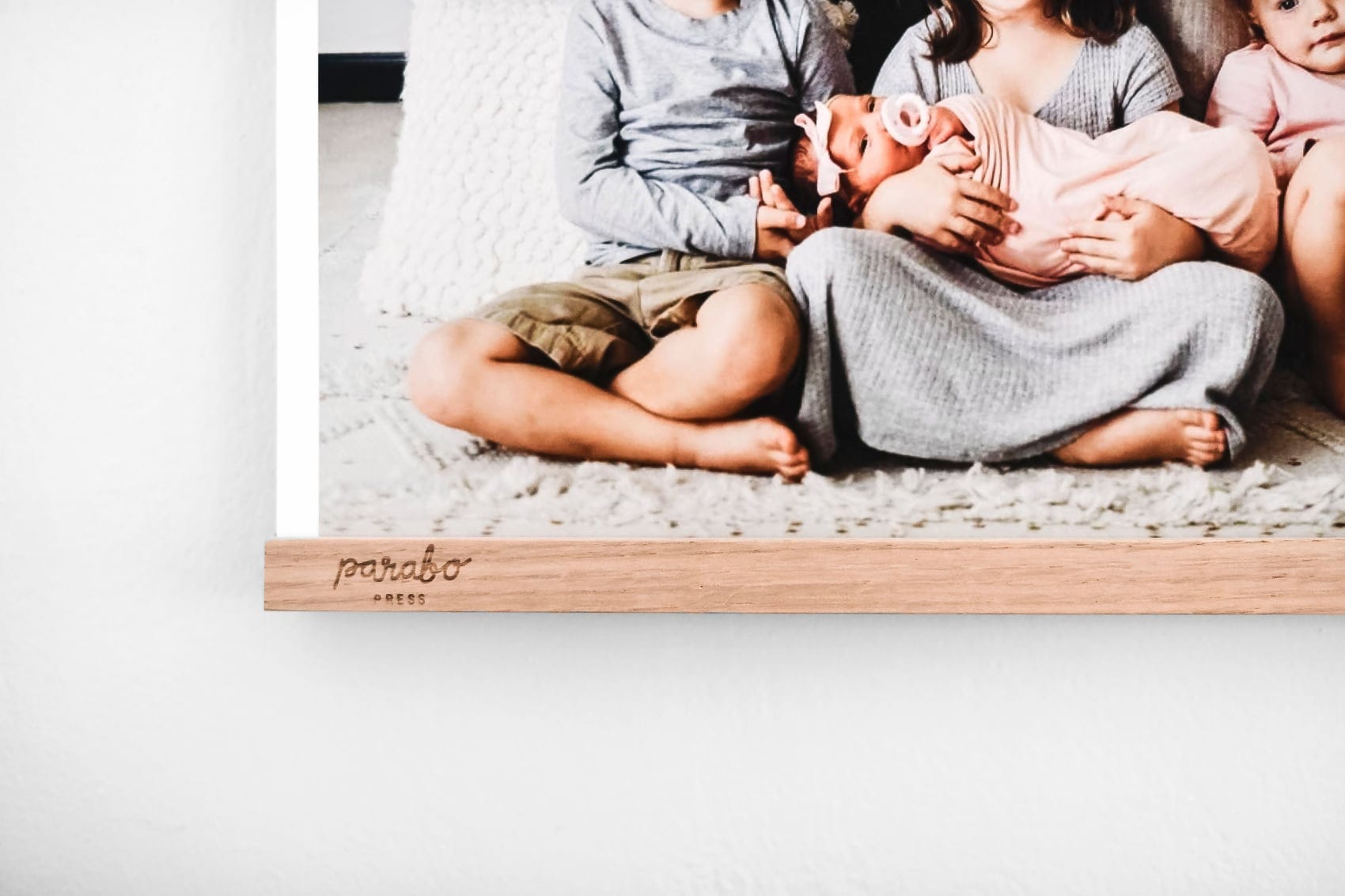 Family photo print hanging on an oak Parabo Wood Poster Rail
